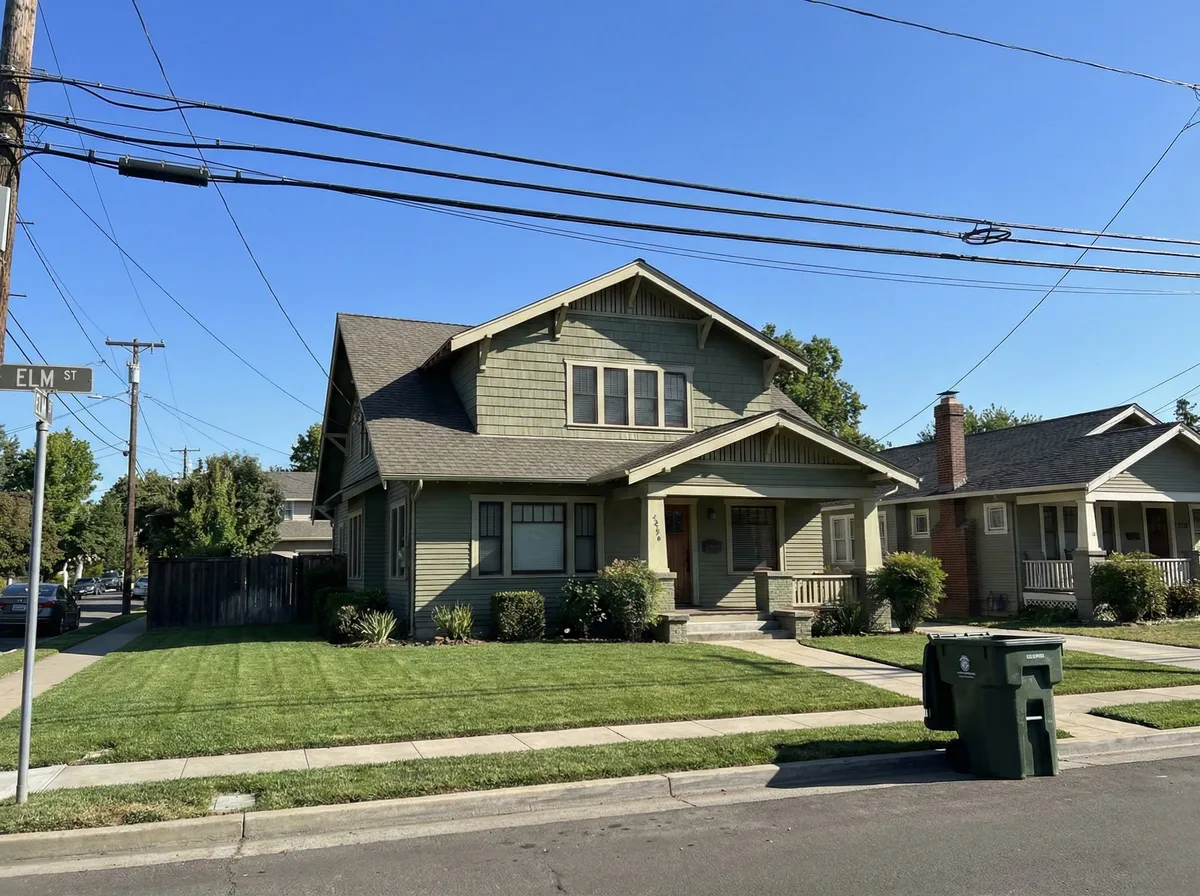 Suburban house exterior with power lines, Elm St street sign, and trash bin on curb